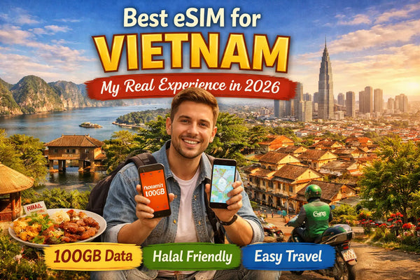 A man smiling while holding two smartphones in front of a scenic Vietnamese landscape.
